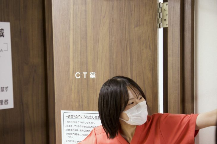 CT室の扉の前で案内するスタッフ